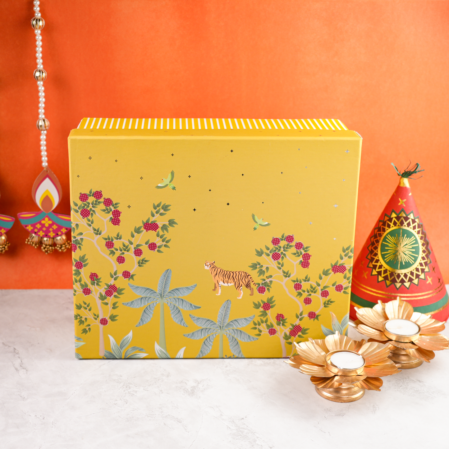 Closed Bagh & Blossom Diwali hamper showing illustrated lid with tiger, birds, and floral artwork, paired with festive diya décor.