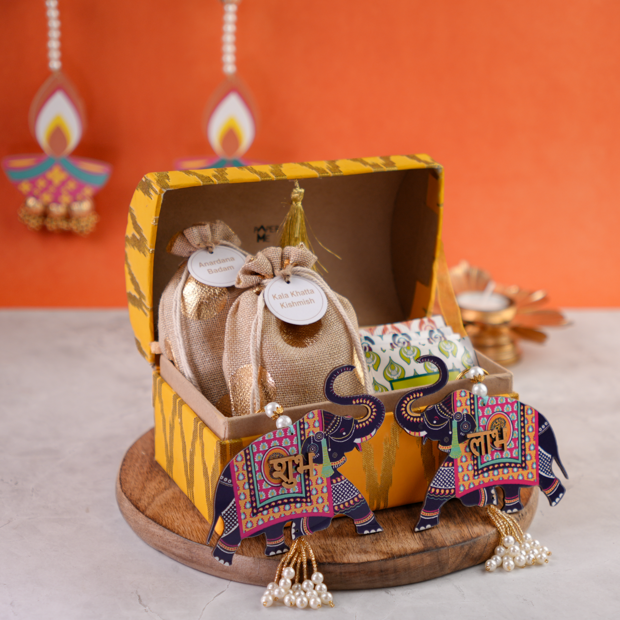 Open ikat trunk showing artisanal treats in jute potlis with Shubh–Labh elephant décor.