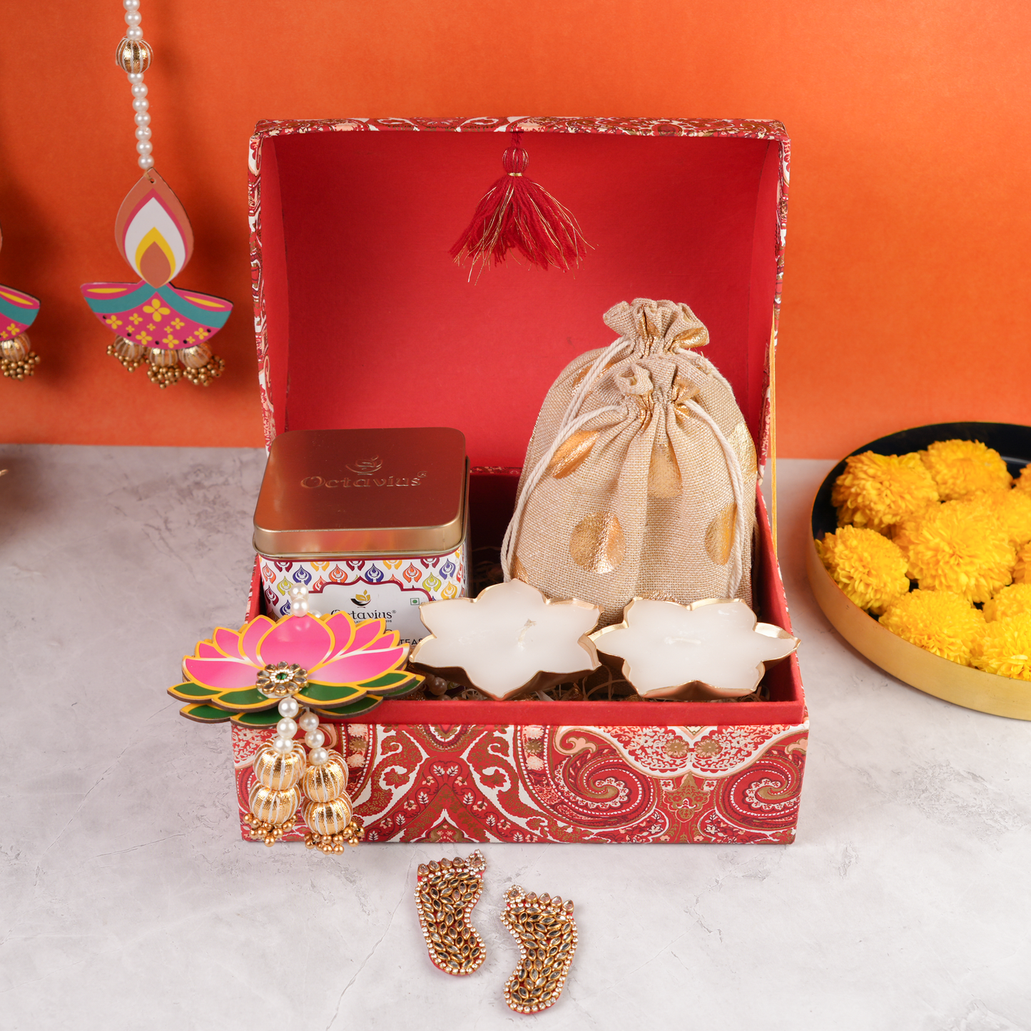 Front display of Paisley Celebration Sandook Box showcasing golden drawstring potli, premium Octavius tea tin, lotus candles, and festive lotus dangler.