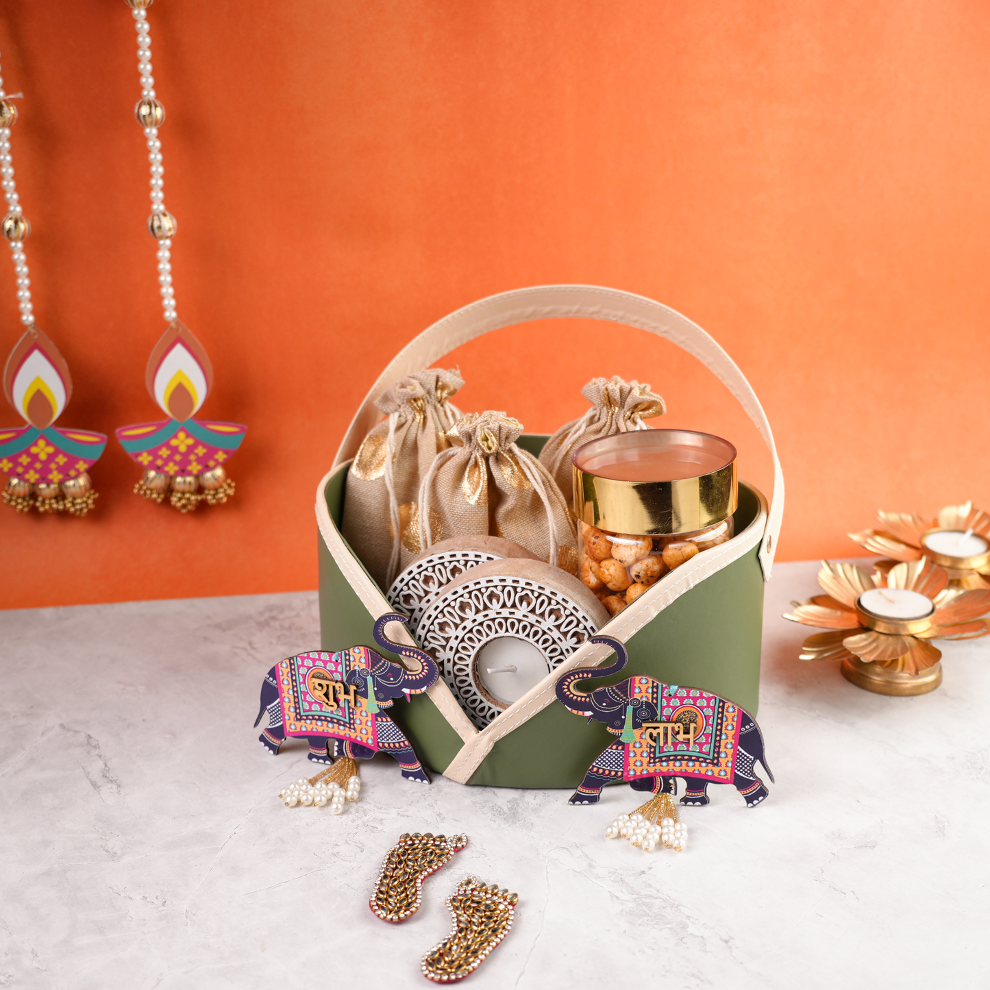 Premium pastel green Diwali gift basket with golden pouches, jar of snacks, tealight holder, and festive decor accents