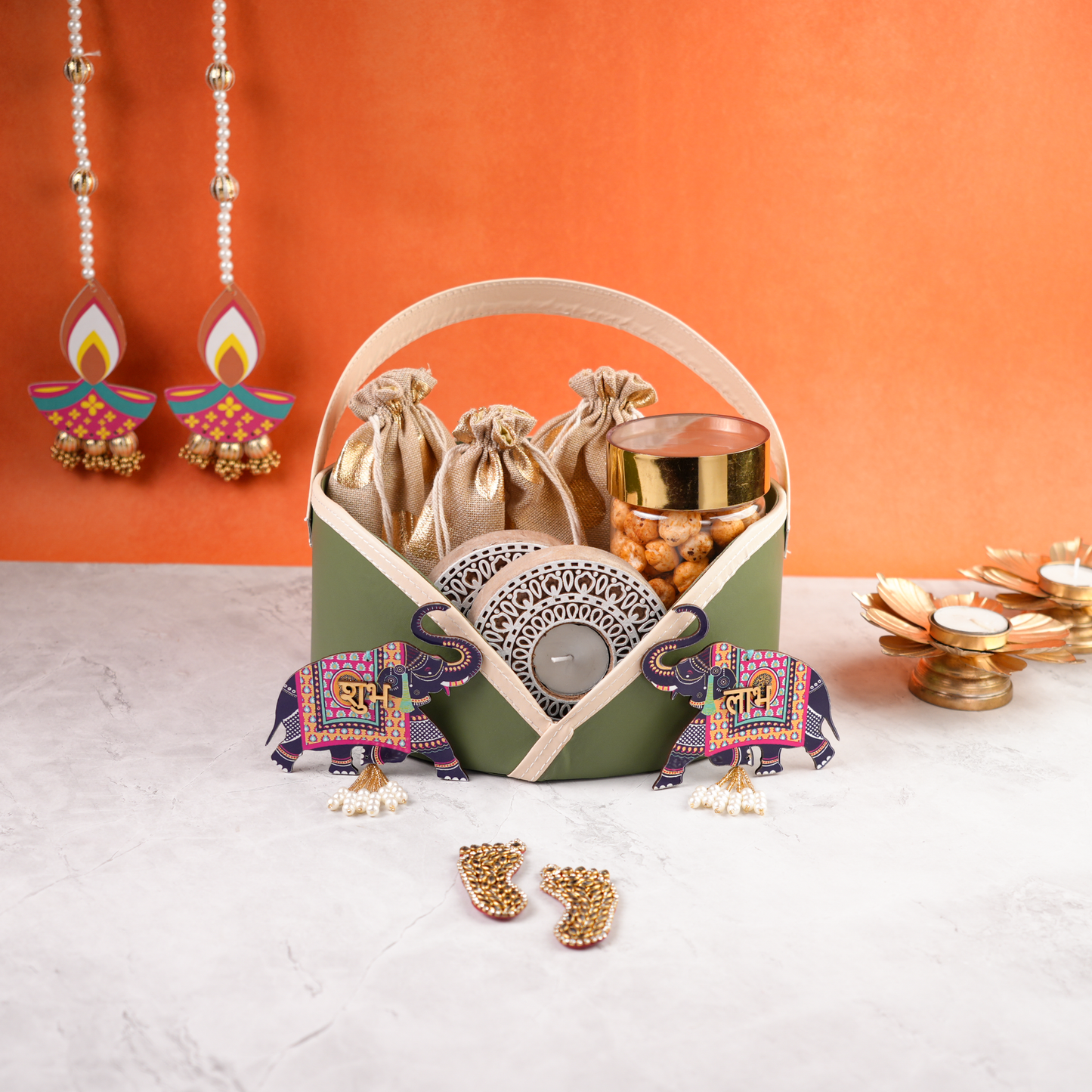 Elegant pastel green Diwali hamper with decorative elephants, tealight candles, and dry snacks, styled for festive gifting.