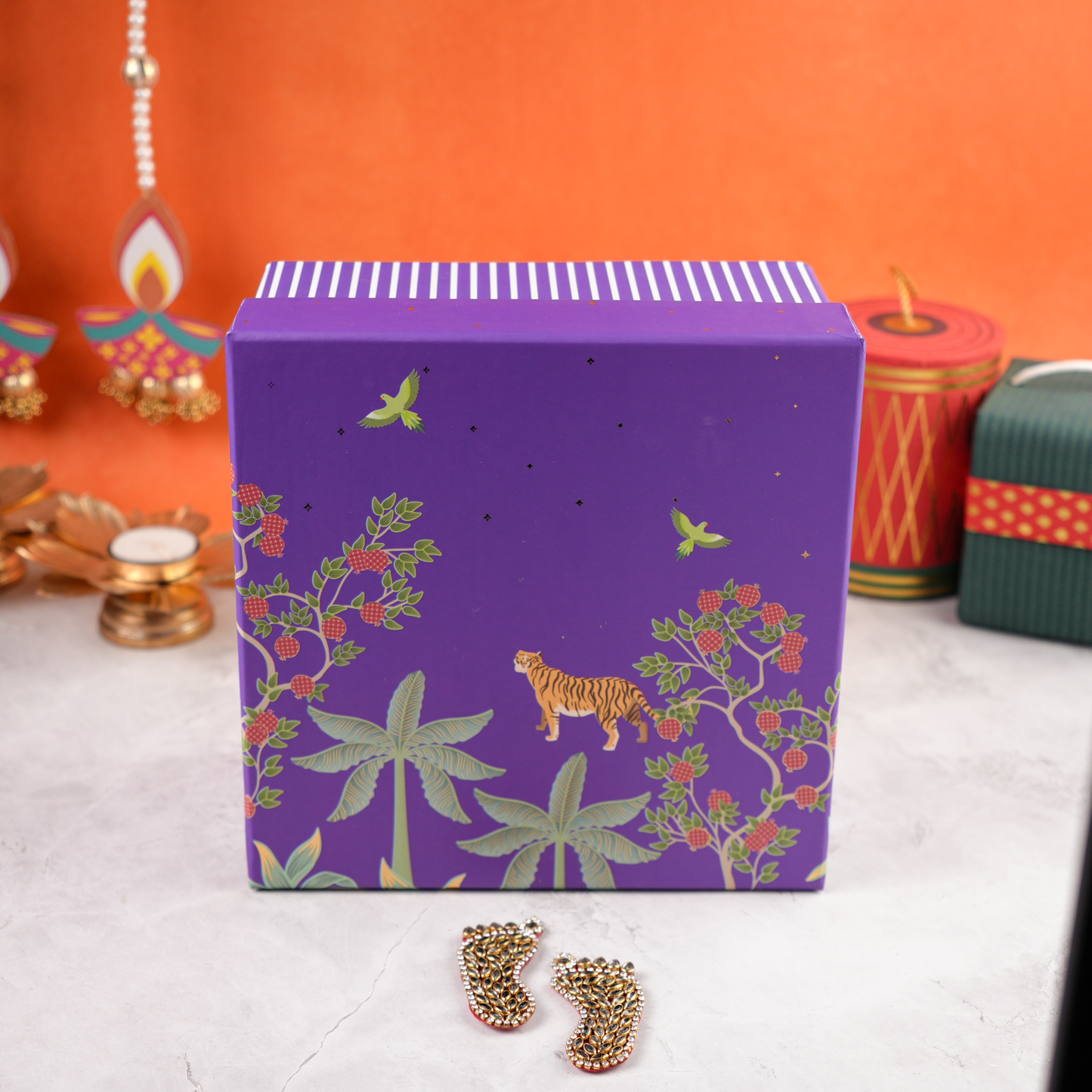 Closed Purple Bagh Diwali Hamper, purple keepsake gift box with golden ribbon, tiger and floral heritage design, placed on marble surface.