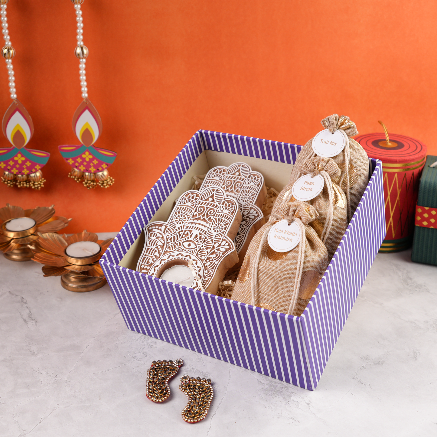 Open Purple Bagh Diwali Hamper showing festive potlis, carved tealight holders, and assorted treats in purple illustrated gift box.