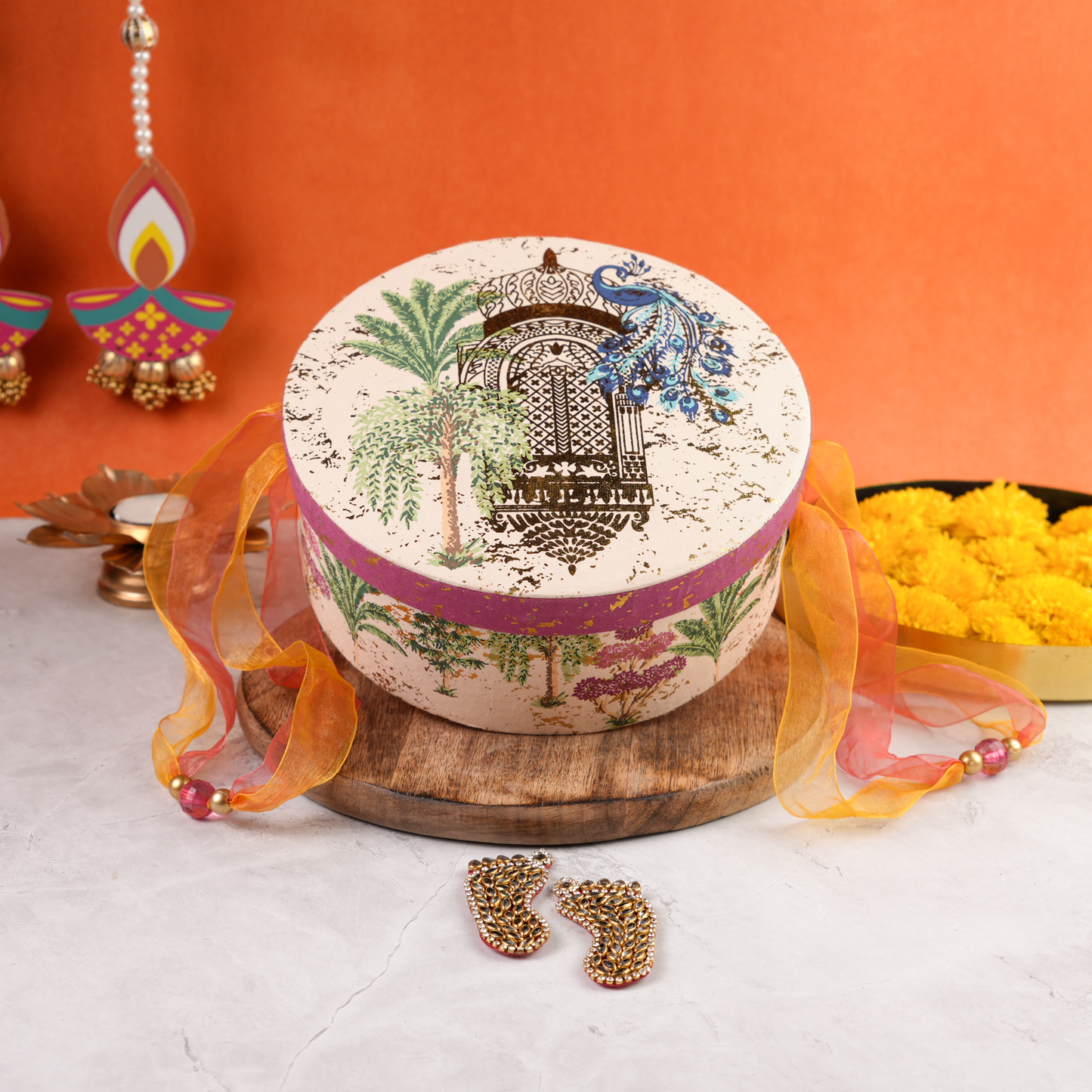 Closed Vanmahal Diwali Hamper round keepsake box with peacock patterm and diwali backdrop.