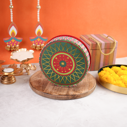 Chakri Diwali Gift Pack closed round cracker-shaped box in green and red festive artwork, placed on wooden base with Diwali décor.
