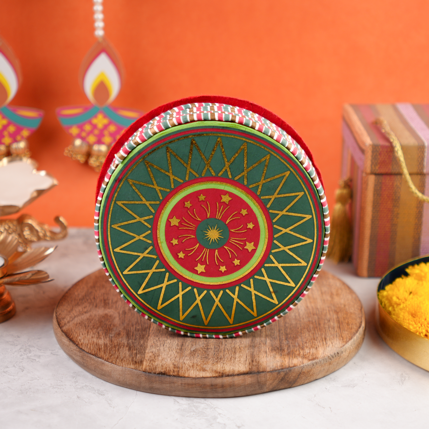 Chakri Diwali Gift Pack round cracker-shaped gift box with colorful green and red chakri artwork, photographed on wooden base with festive backdrop.