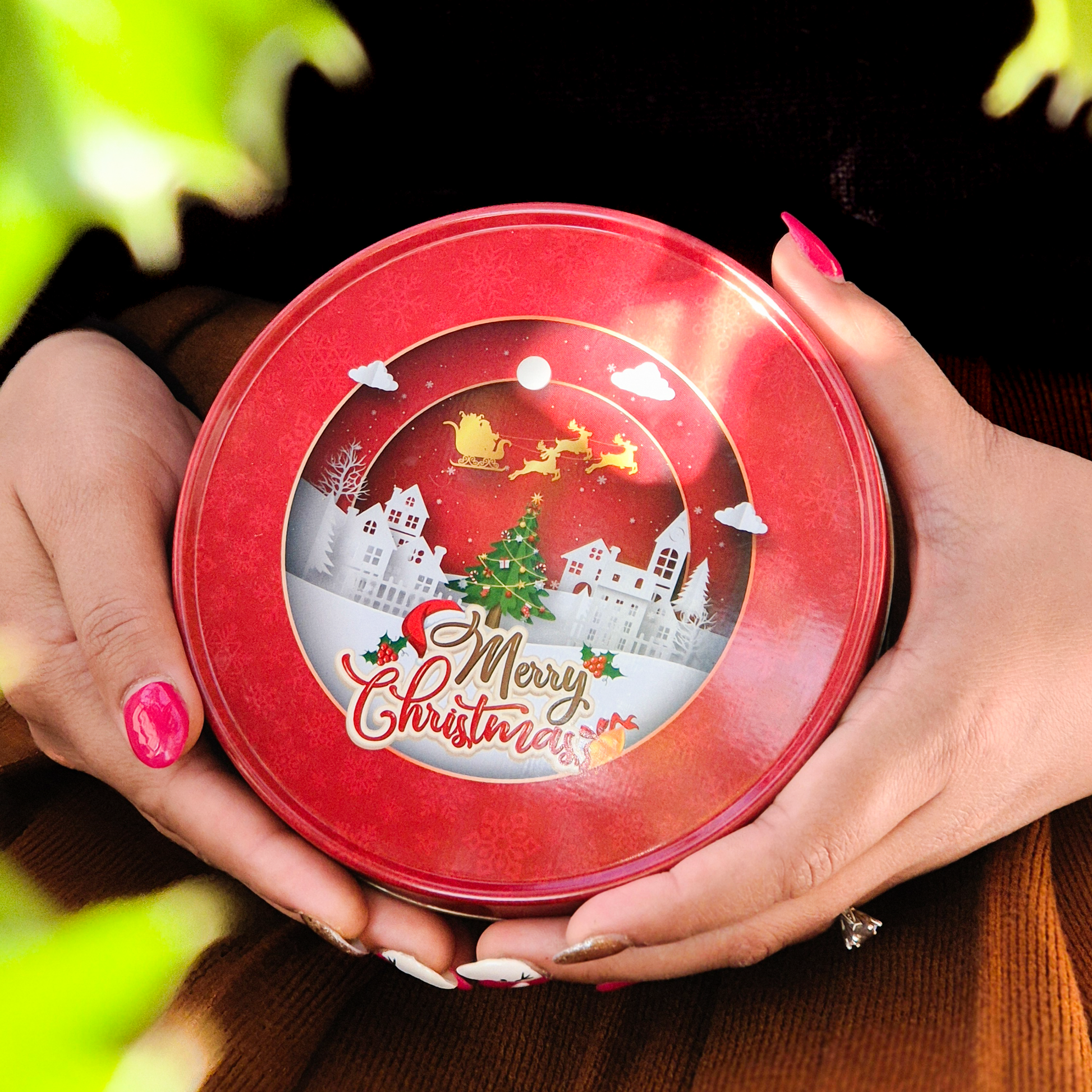 Round Christmas-themed cookie tin filled with red velvet cookies, shown from a top angle.