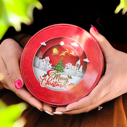 Round Christmas-themed cookie tin filled with red velvet cookies, shown from a top angle.