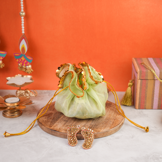 Festive Potli Gift Pack front wide view – elegant green organza potli with golden sequin detailing, placed on a wooden base for Diwali gifting.