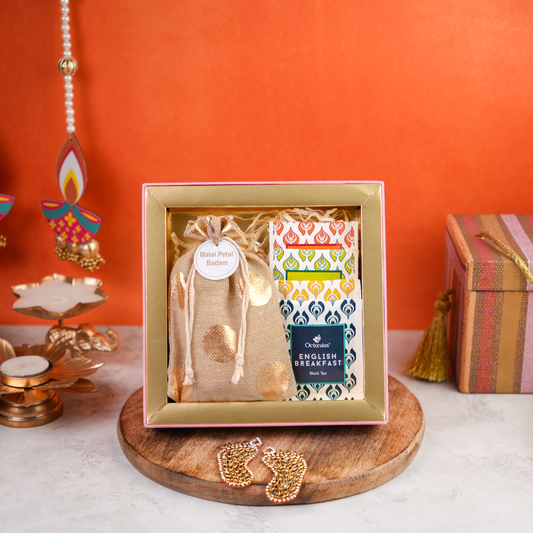 Open front close-up of Floral Budget Diwali Gift Box showing Malai Petal Badam in a golden potli with assorted English Breakfast tea packs, styled on a wooden platter with festive diyas.
