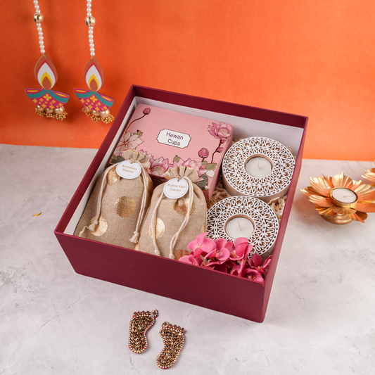 Open Garnet Glow Diwali Hamper showing hawan cups, festive potlis, and carved white tealight holders in maroon box.