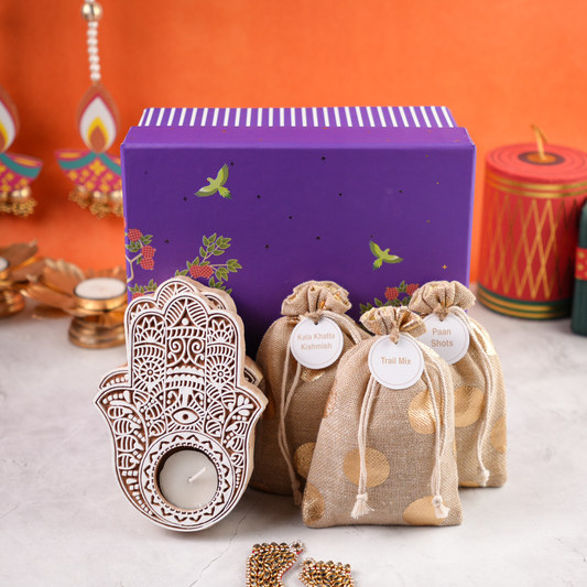 Purple Bagh Diwali Hamper contents flat lay – festive potlis, carved white tealight holders, and assorted artisanal gift items styled for Diwali.